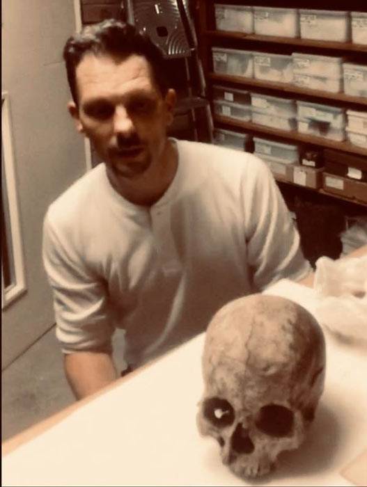 David Atkins kneeling in front of what he long believed was the oldest British skull. (David Adkins / DerbyShireLive)