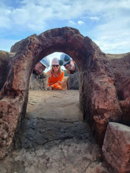 Excavation team staring down the flue of the Roman pottery kiln