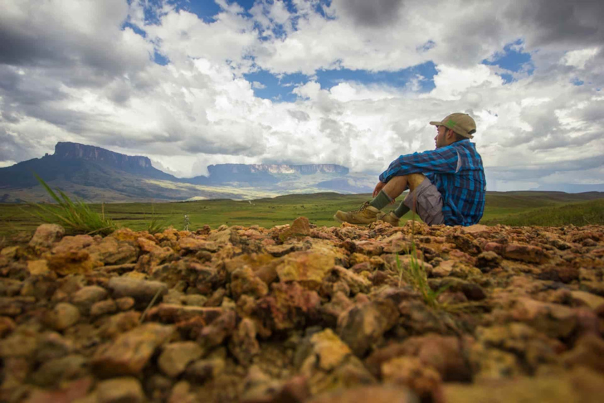 A traveler sitting on the rocky, alien terrain of Mount Roraima's plateau