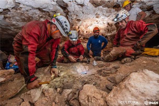 Archaeologists of the National Institute of Anthropology and History (INAH) observe fragments of pottery in a cave, as part of the archaeological work accompanying the construction of a controversial new train. (Oficina Península de Yucatán de la SAS-INAH)