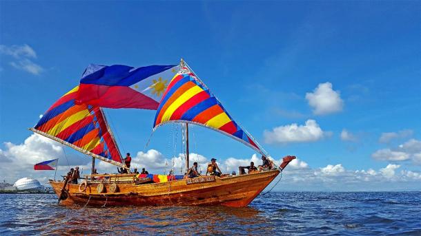 Balangay boat in the waters of Manila Bay with large Philippine flag (Fung360 / CC BY-SA 4.0)