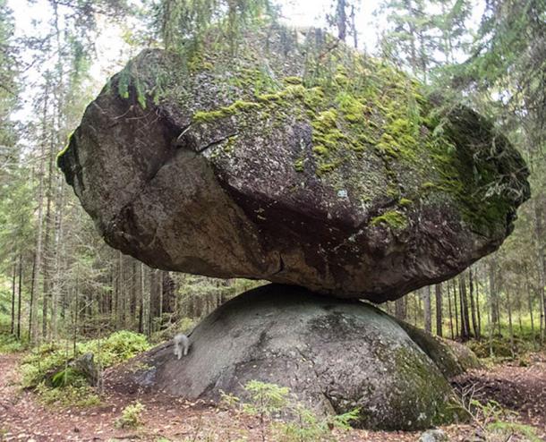 A large precarious boulder called Kummakivi (”Strange stone”), located in Ruokolahti, southeastern FInland. A white miniature schnauzer under it gives an idea of the scale. (Kotivalo/CC BY-SA 4.0)