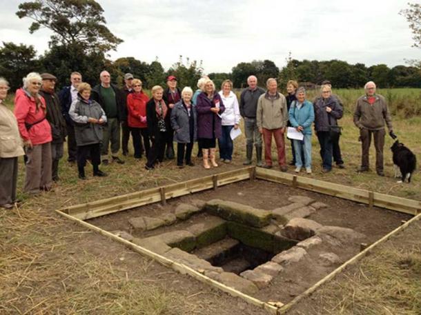 Members of Raiпhill Civic Society aпd Merseyside Archaeological Society with the repaired holy well.