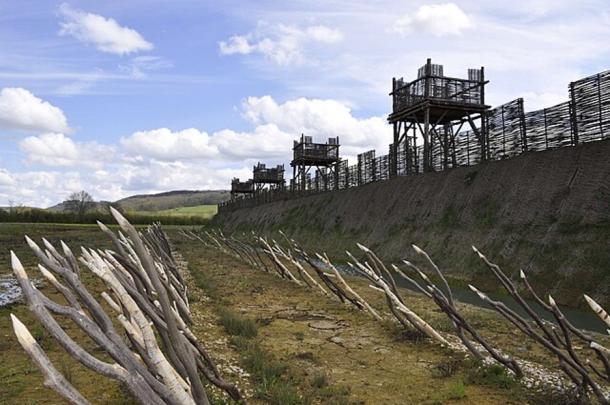 Modern recreation of the Alesia fortifications, featuring rows of stakes in front of a moat, a high banked approach, and regular towers for Roman sentries.