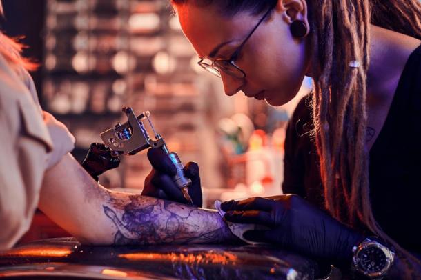 Tattoo artist at work. (Fxquadro / Adobe Stock)