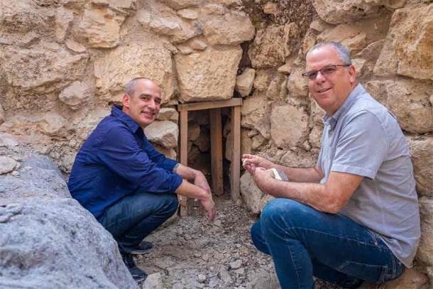 Dr Joe Uziel of the Israel Antiquities Authority (left) and Professor Yuval Gadot of Tel Aviv University with a bat skull at the wall in the City of David. (IAA)