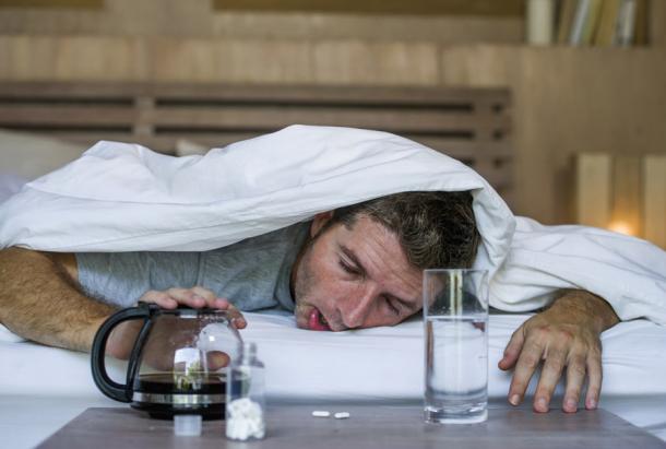 A young exhausted and wasted man with a hangover after a night of partying. Even today, hangover cures vary between lots of water to traditional remedies. (TheVisualsYouNeed / Adobe Stock)