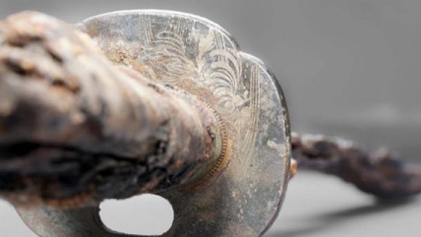 Detailed view of the Japanese swords guard plate (tsuba) with the inlaid and melted chrysanthemum motif and the water lines.