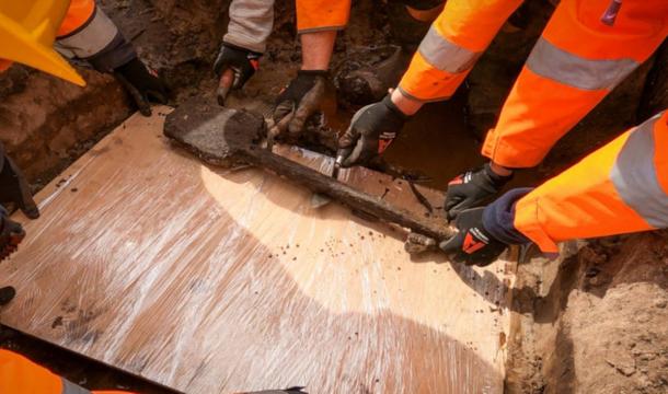 Archaeologists removiing the 3,500-year-old wooden spade from the finde site.