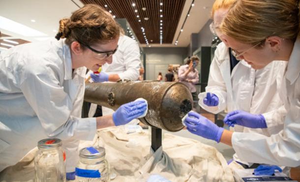 Nautical Archaeology Program graduate students Kimberly Breyfogle ’23 (left), Alyssa Carpenter ’22 (center) and Marissa Agerton ’25 (right) gently clean the exterior of a four-pound bronze cannon used in the Battle of the Alamo.