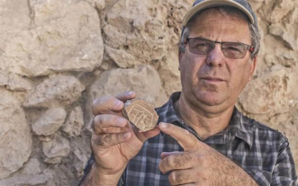 El profesor Yuval Gadot, de la Universidad de Tel Aviv, posa con un sello de la era persa descubierto en la excavación de un estacionamiento en Jerusalén. (Shai Halevy / Autoridad de Antigüedades de Israel)