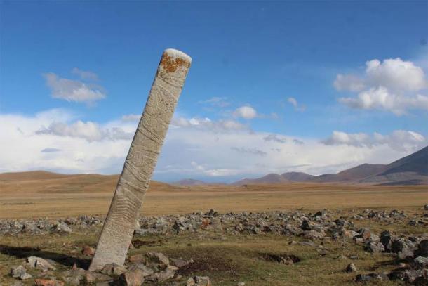 O piatră de cerb înclinată așezată în fața a zeci de movile mici de piatră care conțin înmormântări de cai sacrificați ritual la monumentul din epoca bronzului din situl Ikh Tsagaanii Am, provincia Bayankhongor, Mongolia centrală.  (William Taylor)