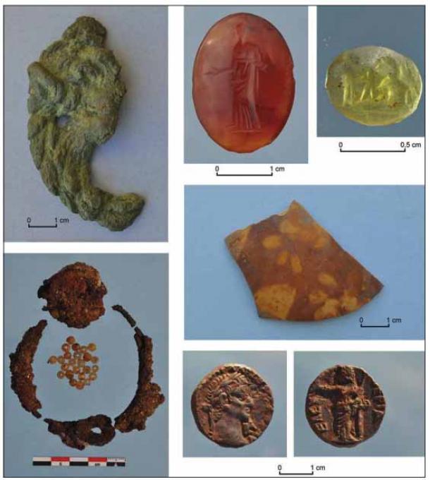 The wealth that was coming into and passing through Berenice is evident from the remains. Selection of finds: (clockwise from bottom left) iron collar decorated with beads; bronze lion's protome from the Great Temple; two intaglios; painted ostrich eggshell fragments; bronze coin of Roman emperor Caligula (Steven Sidebotham and K. Braulińska)